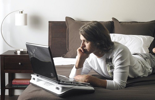 person using laptop in bed with cooling pad