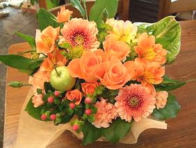 オレンジ色の花のアレンジメントは、明るく元気いっぱいな方に